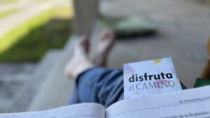 Disfruta el camino se lee en un marcador de un libro abierto, y unos pies - Asun Adá
